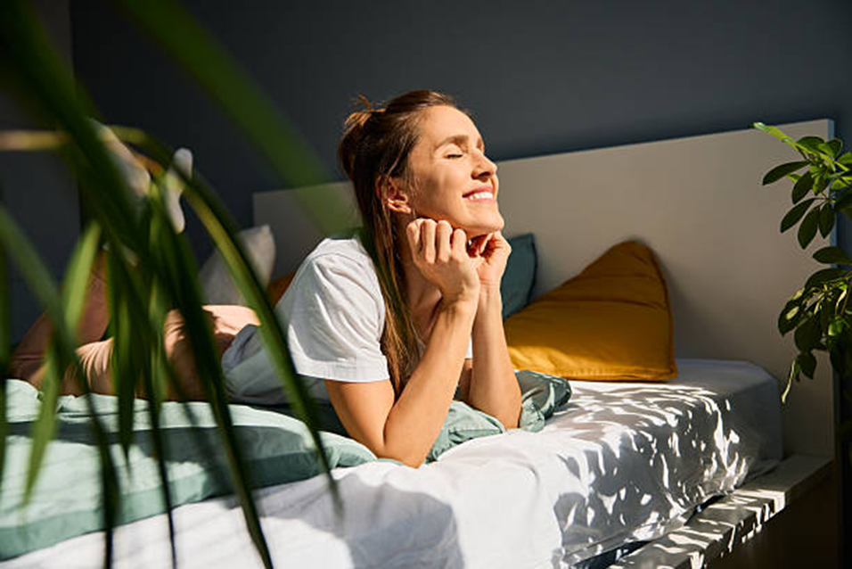 Woman smiling with closed eyes next to a houseplant