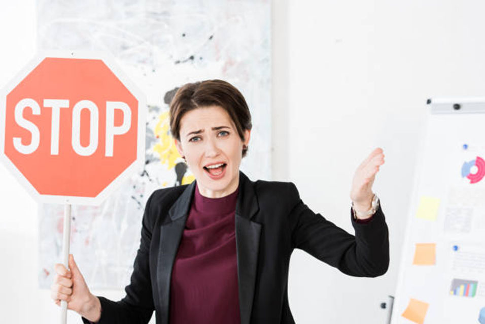 Frustrated woman holding a stop sign, overwhelmed by trying to understand everything