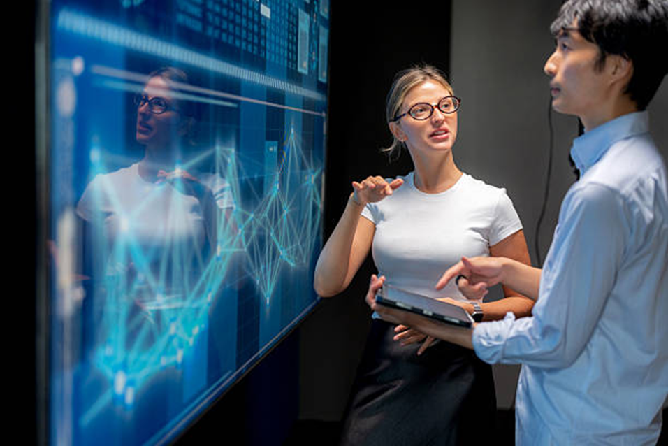 Woman and man talking in front of a digital screen