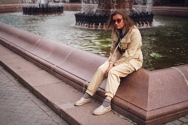 Woman sitting alone on a fountain edge, lost in thoughts of someone