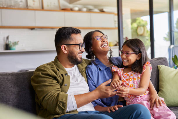 Laughing family of three on a sofa, enjoying a happy life together