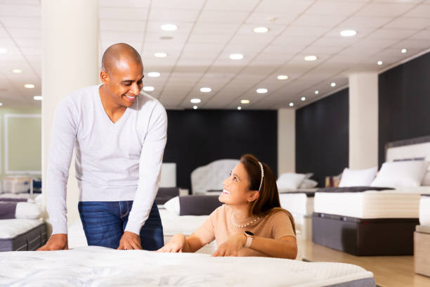 Smiling couple testing a mattress together, sharing a warm, appreciative moment