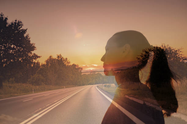 Woman silhouetted on an open road at sunset